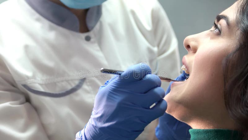 Dentista in guanti che esamina paziente