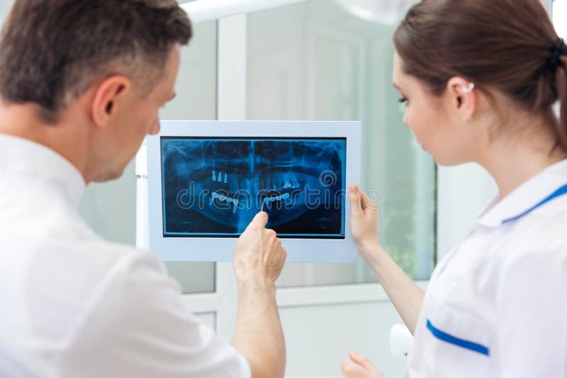 Dentista maschio che mostra qualcosa sul monitor del computer fotografia stock Dentista maschio che mostra qualcosa sul monitor del computer fotografia stock