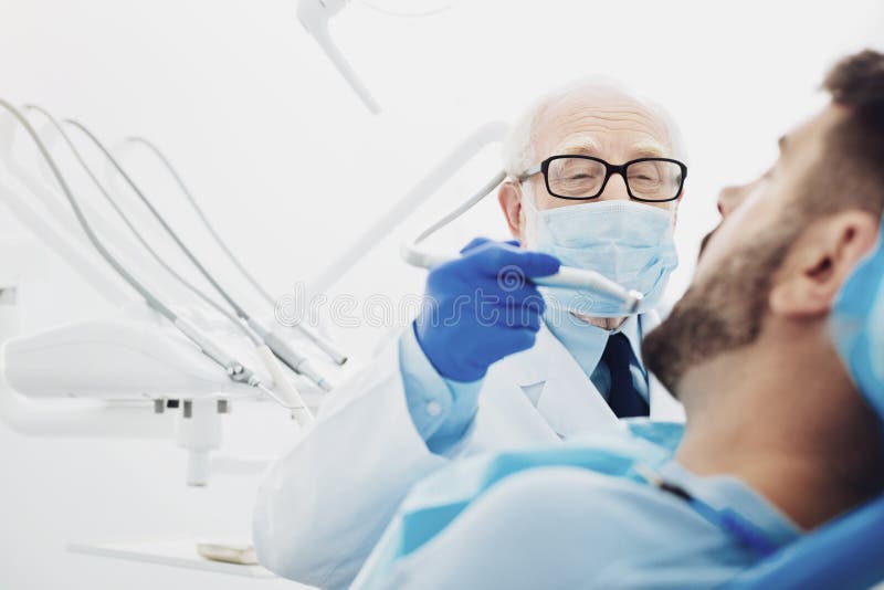 Dentista maschio con esperienza che sostituisce dente fotografie stock Dentista maschio con esperienza che sostituisce dente fotografie stock