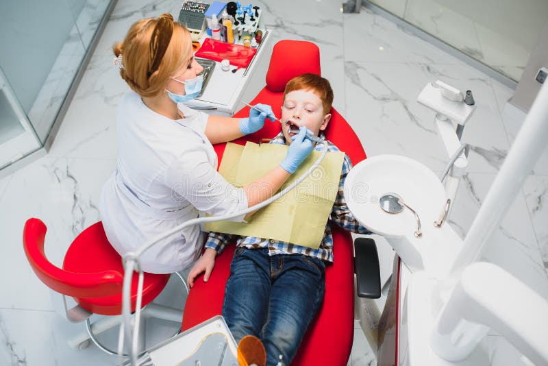 Pediatric dentist examining a little boys teeth in the dentists chair at the dental clinic. Pediatric dentist examining a little boys teeth in the dentists chair at the dental clinic.