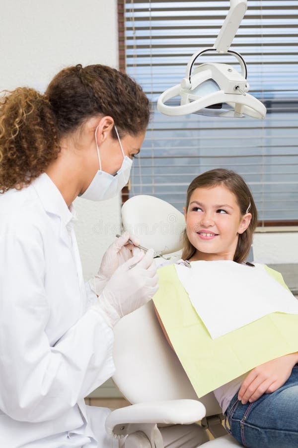 Pediatric dentist speaking with little girl in the dentists chair at the dental clinic. Pediatric dentist speaking with little girl in the dentists chair at the dental clinic