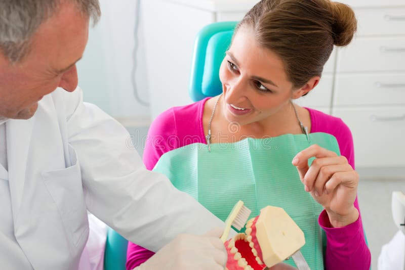 Dentista que explica a escovadela de dentes ao paciente fotografia de stock royalty free
