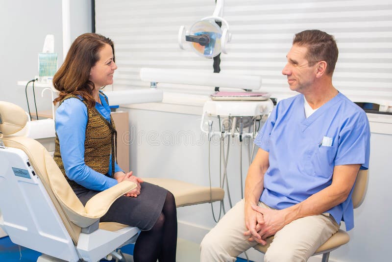 Dentista que fala ao conceito do paciente, do stomatology e dos cuidados médicos imagem de stock Dentista que fala ao conceito do paciente, do stomatology e dos cuidados médicos imagem de stock