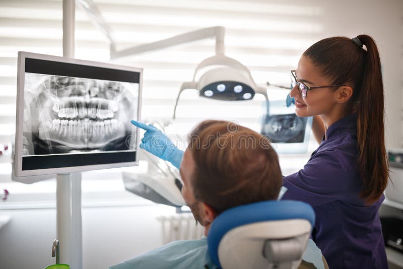 Dentista que mostra a metragem do raio X dos dentes ao paciente