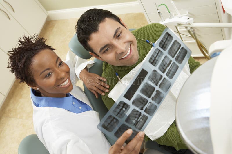 Dentista que mostra o raio X do dente ao paciente
