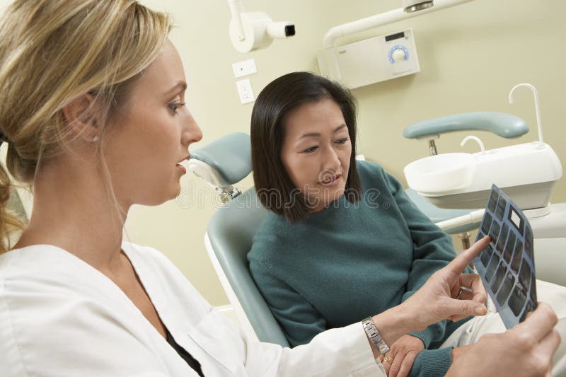 Dentista que mostra o relatório do raio X ao paciente