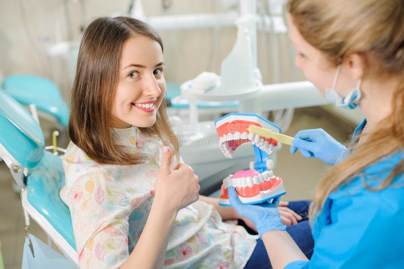 Dentista que muestra el modelo dental del mandíbula al paciente en el dentist& x27; clínica de s foto de archivo Dentista que muestra el modelo dental del mandíbula al paciente en el dentist& x27; clínica de s foto de archivo