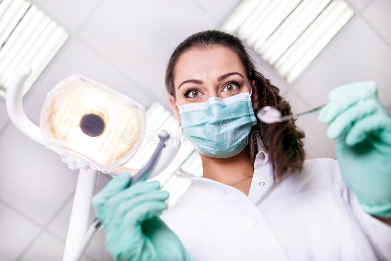 Dentista spaventoso e divertente che lavora con un paziente in wor protettivo fotografia stock libera da diritti Dentista spaventoso e divertente che lavora con un paziente in wor protettivo fotografia stock libera da diritti