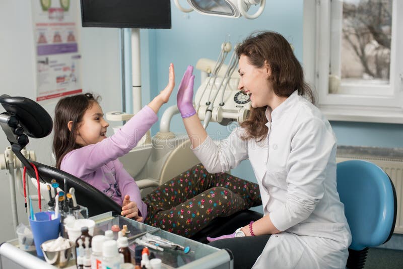 Dentista y niño precioso después de tratar los dientes en la oficina dental de la clínica, de sonreír y de dar alto-cinco Odontol imagen de archivo libre de regalías Dentista y niño precioso después de tratar los dientes en la oficina dental de la clínica, de sonreír y de dar alto-cinco Odontol imagen de archivo libre de regalías