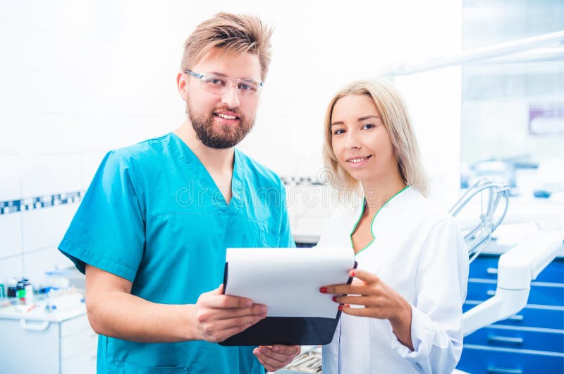 Dentists in uniform looking notes on notepad. Dentists in uniform looking notes on notepad