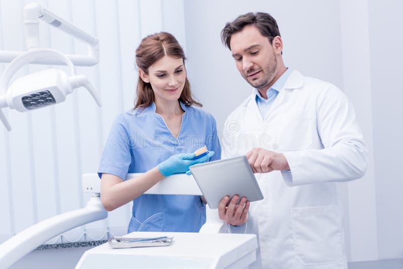 Portrait of young dentists discussing work together and using tablet in dental clinic. Portrait of young dentists discussing work together and using tablet in dental clinic