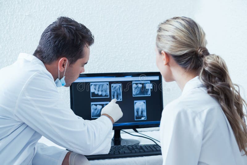 Two concentrated dentists looking at x-ray on computer. Two concentrated dentists looking at x-ray on computer