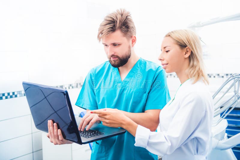 Dentists in uniform working with laptop. Dentists in uniform working with laptop