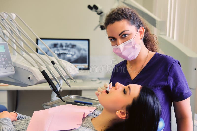 Dentiste examinant les dents femelles du ` s en art dentaire photographie stock Dentiste examinant les dents femelles du ` s en art dentaire photographie stock