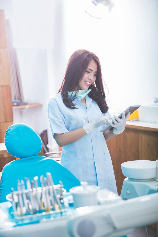 Dentiste féminin avec le comprimé au-dessus de la clinique médicale de bureau images libres de droits Dentiste féminin avec le comprimé au-dessus de la clinique médicale de bureau images libres de droits