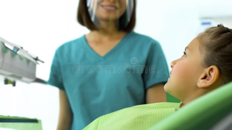 Dentiste féminin souriant à l'adolescente, dents de examen d'enfant de docteur amical photo libre de droits Dentiste féminin souriant à l'adolescente, dents de examen d'enfant de docteur amical photo libre de droits