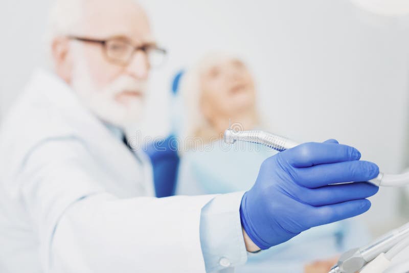 Dentiste masculin focalisé prenant l'instrument image stock Dentiste masculin focalisé prenant l'instrument image stock