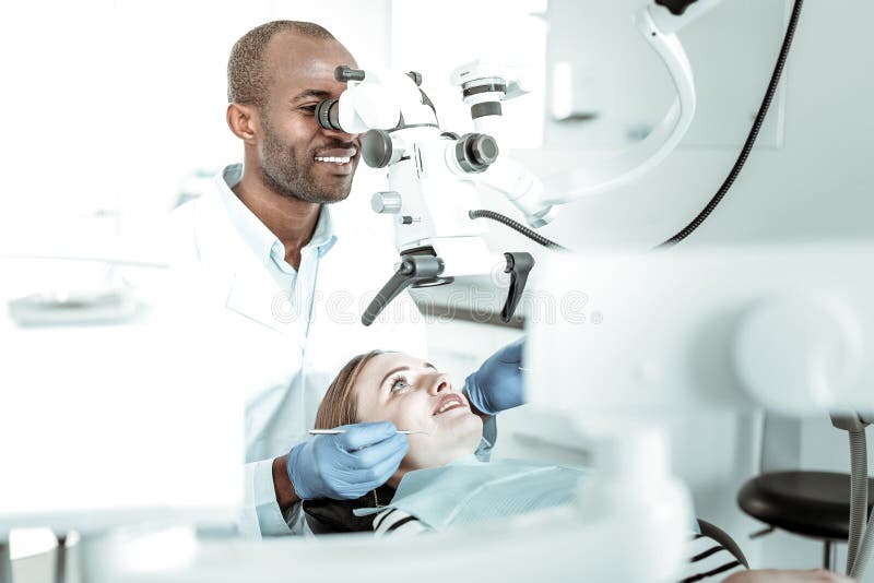 Dentiste professionnel à l'aide de la machine pour une meilleure vue photographie stock libre de droits Dentiste professionnel à l'aide de la machine pour une meilleure vue photographie stock libre de droits