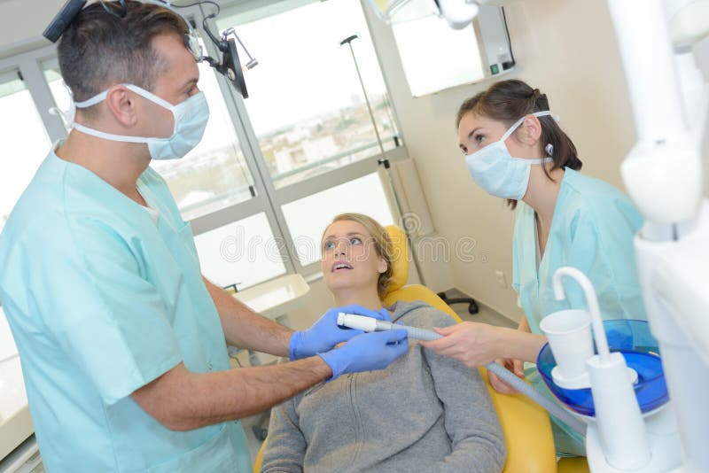 Dentiste tenant le tuyau d'aspiration photographie stock libre de droits Dentiste tenant le tuyau d'aspiration photographie stock libre de droits