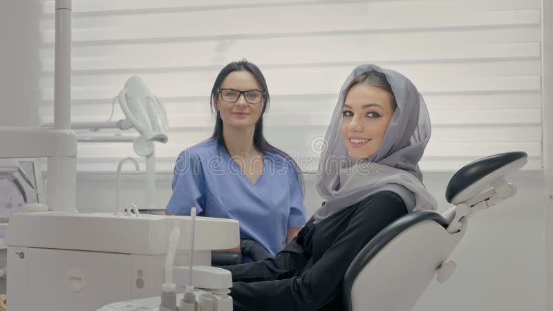 Dentiste travaillant au bureau. visage du jeune patient proche. jeune fille en foulard sur la tête assise sur le fauteuil des dent clips vidéos