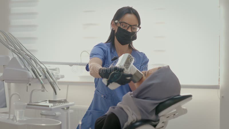 Dentiste travaillant au bureau. visage du jeune patient proche. jeune fille en foulard sur la tête assise sur le fauteuil des dent clips vidéos