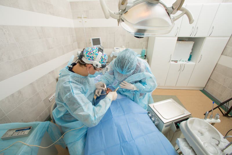 Dentistes avec un patient et un assistant pendant une intervention dentaire Dentiste Concept Chirurgie dentaire procédé d'opérati photo libre de droits Dentistes avec un patient et un assistant pendant une intervention dentaire Dentiste Concept Chirurgie dentaire procédé d'opérati photo libre de droits