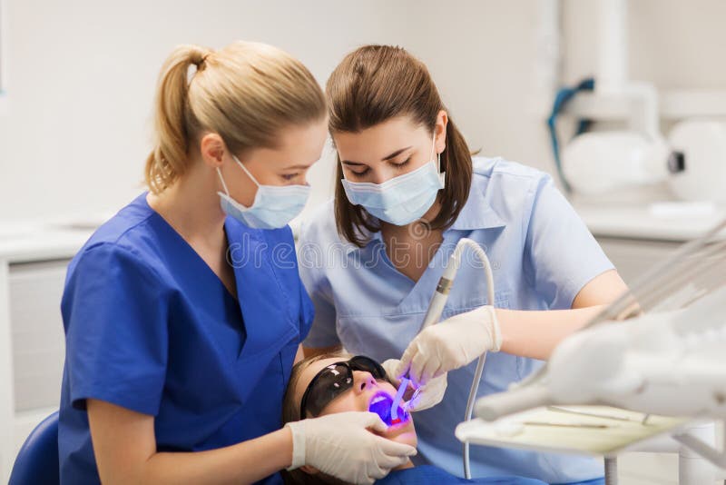 Dentistes féminins traitant les dents patientes de fille images libres de droits Dentistes féminins traitant les dents patientes de fille images libres de droits