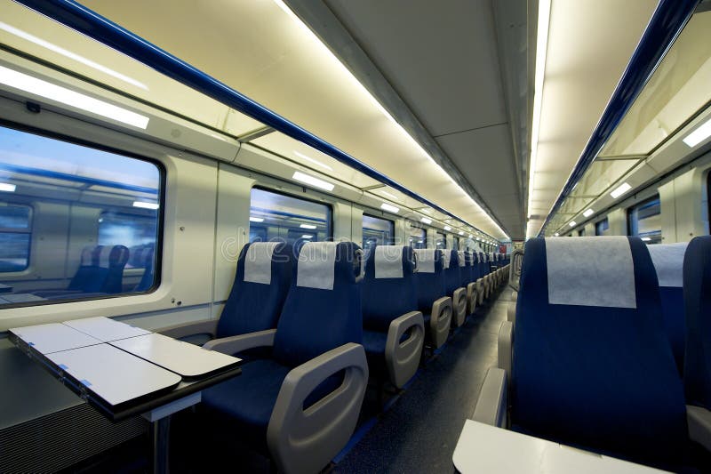 Empty interior of a passenger train car (aka coach or carriage). Rows of unoccupied seats and folding tables in economy class. Public transport. Empty interior of a passenger train car (aka coach or carriage). Rows of unoccupied seats and folding tables in economy class. Public transport.