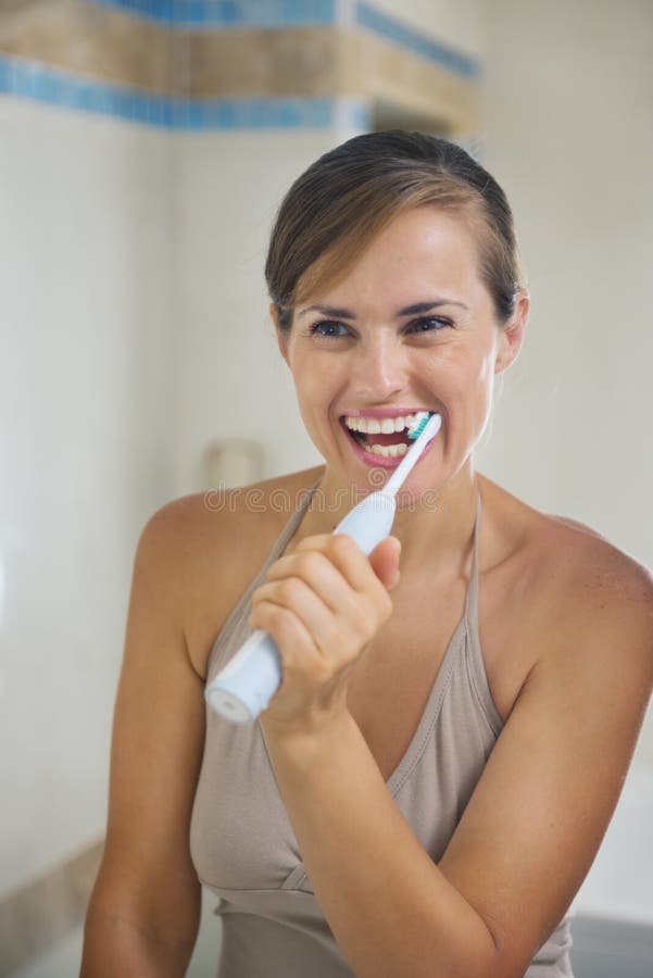 Dents de brossage de femme avec la brosse à dents électrique photo libre de droits Dents de brossage de femme avec la brosse à dents électrique photo libre de droits