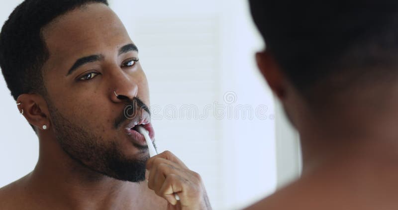 Dents de brossage de jeune homme bel métisse dans la salle de bain. banque de vidéos
