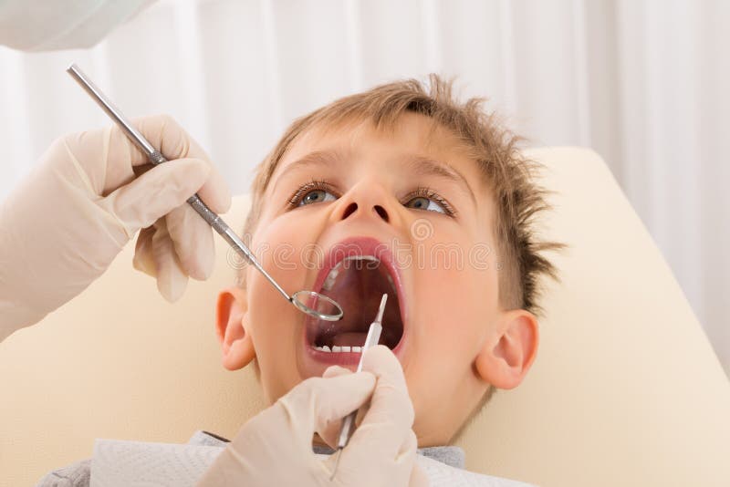 Dents de examen de main du ` s de dentiste de patient d'enfant photographie stock Dents de examen de main du ` s de dentiste de patient d'enfant photographie stock