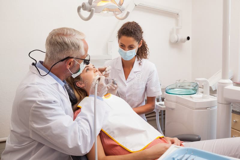 Dentysta i asystent egzamininuje pacjentów zęby obraz stock Dentysta i asystent egzamininuje pacjentów zęby obraz stock