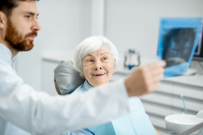 Dentysta pokazuje promieniowanie rentgenowskie stara kobieta w dentall biurze zdjęcia stock Dentysta pokazuje promieniowanie rentgenowskie stara kobieta w dentall biurze zdjęcia stock