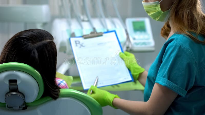 Dentysta pokazuje żeńskiego cierpliwego ubezpieczenie przed procedurą, zdrowie recepta fotografia stock Dentysta pokazuje żeńskiego cierpliwego ubezpieczenie przed procedurą, zdrowie recepta fotografia stock
