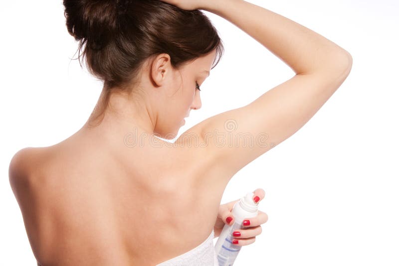 Young woman applying deodorant, studio white