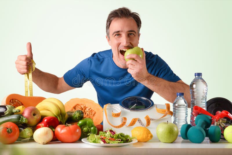 Deportista comiendo manzana con frutas y verduras y pesaje foto de archivo libre de regalías