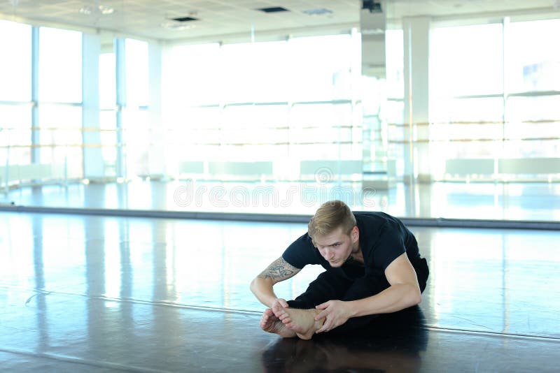 Male athlete doing handstand with legs spread out. Young person training near big mirrors at studio. Concept of dance moves and styles from breakdancing. Male athlete doing handstand with legs spread out. Young person training near big mirrors at studio. Concept of dance moves and styles from breakdancing.