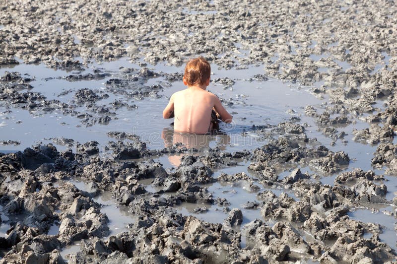 Deposits of natural healing clay. The child gladly accepts mud b