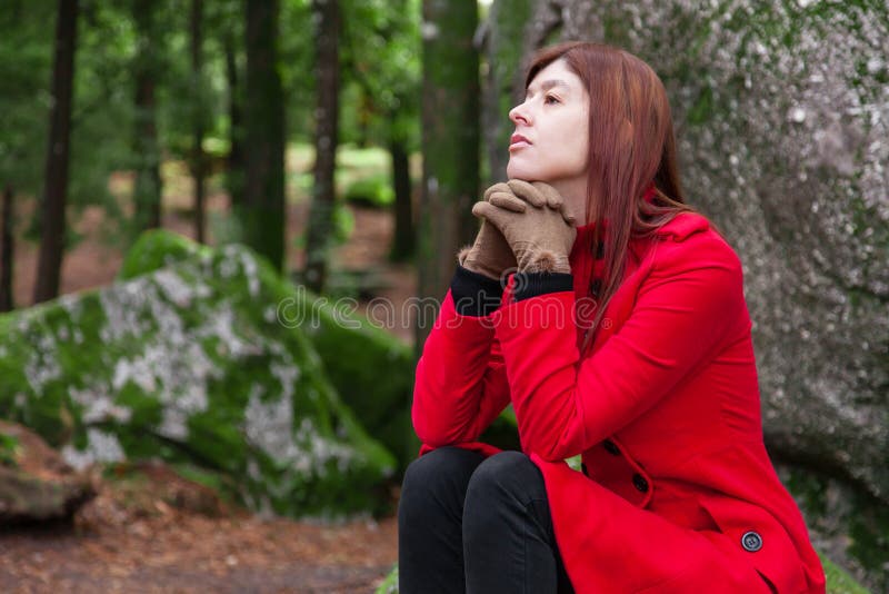 Depresión deprimida y triste de la sensación de la mujer joven que se sienta en el bosque, mirando para arriba con el pensamiento foto de archivo libre de regalías Depresión deprimida y triste de la sensación de la mujer joven que se sienta en el bosque, mirando para arriba con el pensamiento foto de archivo libre de regalías