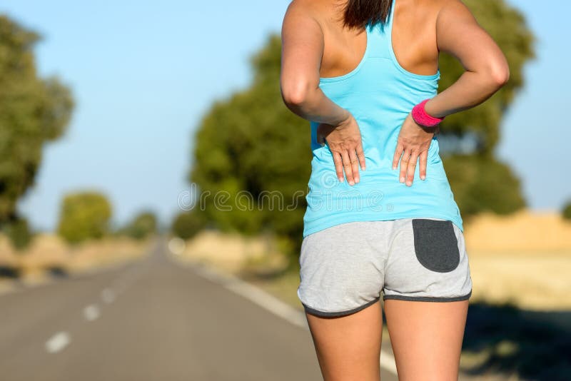 Female runner athlete low back injury and pain. Woman suffering from painful lumbago while running in rural road. Female runner athlete low back injury and pain. Woman suffering from painful lumbago while running in rural road.