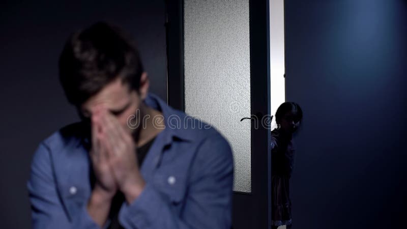 Depressed father crying in room, little daughter opening door, pain of loss stock image Depressed father crying in room, little daughter opening door, pain of loss stock image