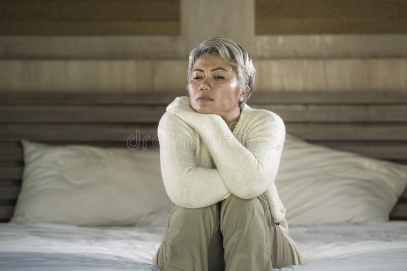 Depressed and sad grey hair mature woman crying lonely sitting on bed suffering crisis in pain and depression problem feeling lost