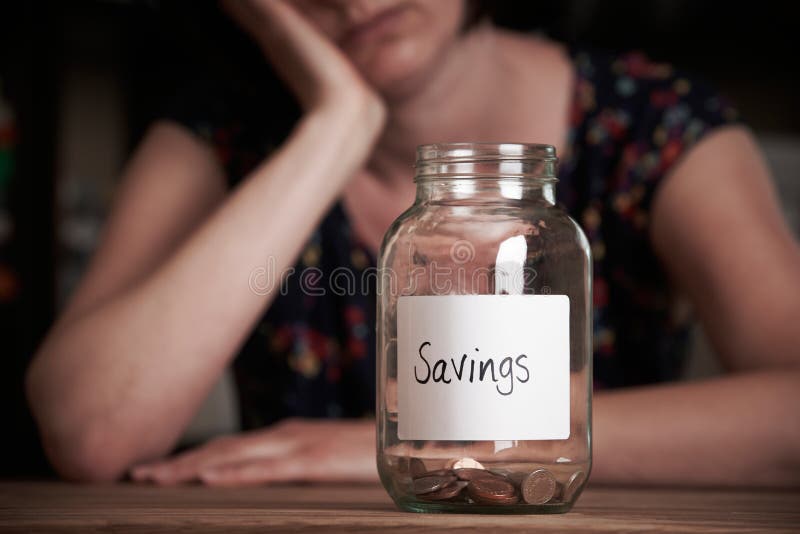 Depressed Woman Looking At Empty Jar Labelled Savings