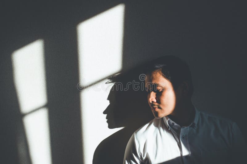 Depression. a Depressed Man Leaning Against the Wall is Hit by Sunlight in an Empty Room. Stock