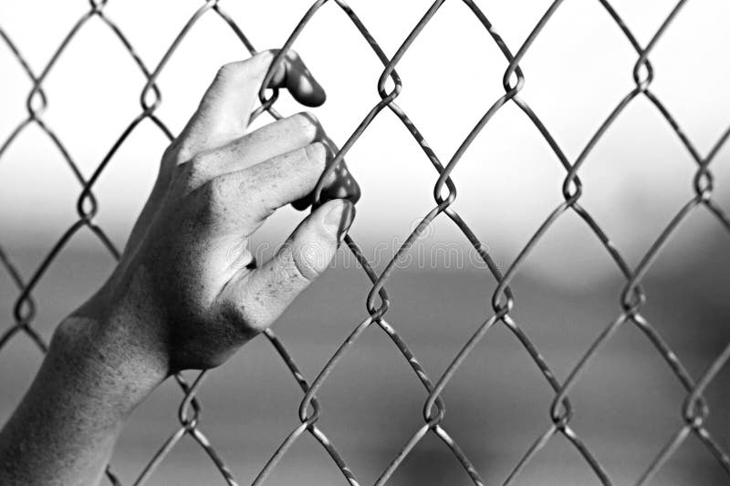 Depression - close up of hand on chain-link fence. Limited depth of field, converted to black and white with added grain. Depression - close up of hand on chain-link fence. Limited depth of field, converted to black and white with added grain.