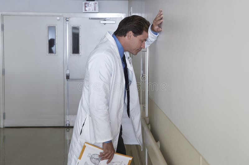 Deprimerad doktor Leaning Against Wall arkivfoton Deprimerad doktor Leaning Against Wall arkivfoton