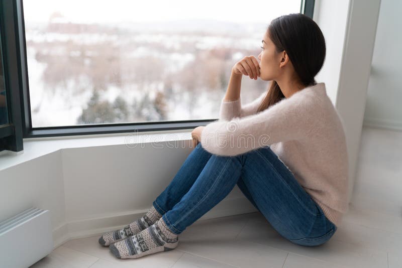 Deprimiertes Gefühl des jungen Mädchens leider ein einsames besorgt, das Fenster im Winter raus auf die Zukunft. unglückliche asia