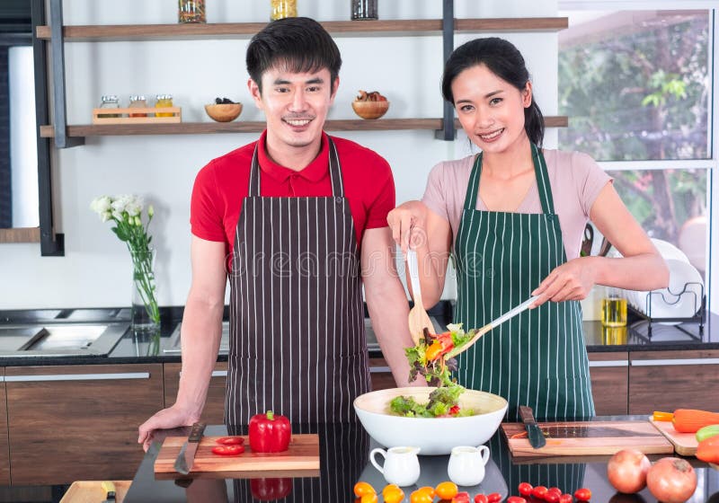 Der asiatischen jungen Paare im Schutzblech, machen zusammen kochen Frauenmischungs-Salatso?e mit Gem?se in der gro?en Sch?ssel stockfotografie Der asiatischen jungen Paare im Schutzblech, machen zusammen kochen Frauenmischungs-Salatso?e mit Gem?se in der gro?en Sch?ssel stockfotografie