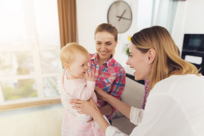 Der Babysitter trifft die Mutter der Kinder und hält das Baby in ihren Armen Das ältere Mädchen umarmt Mutter stockfoto Der Babysitter trifft die Mutter der Kinder und hält das Baby in ihren Armen Das ältere Mädchen umarmt Mutter stockfoto