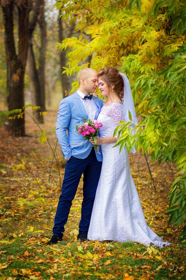 Der Bräutigam und die Braut gehen in den Herbstpark Glückliche Jungvermähltenhaltung an einem gelben Baum lizenzfreies stockfoto Der Bräutigam und die Braut gehen in den Herbstpark Glückliche Jungvermähltenhaltung an einem gelben Baum lizenzfreies stockfoto